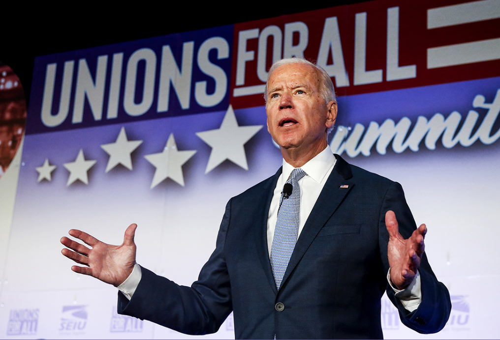 President Biden with his hands out in front of a "Unions For All" Banner